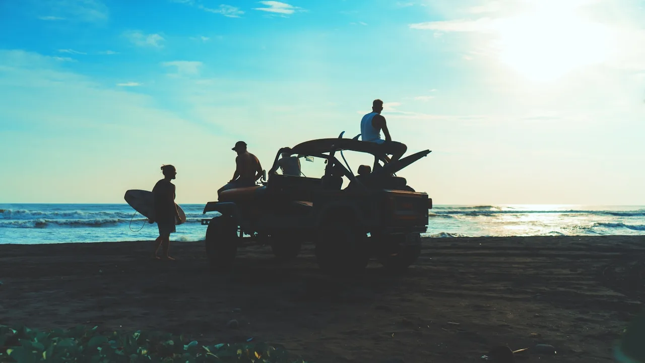 Vintage 1970s Super 8 film still of friends on a pickup truck tailgate with golden sun flare