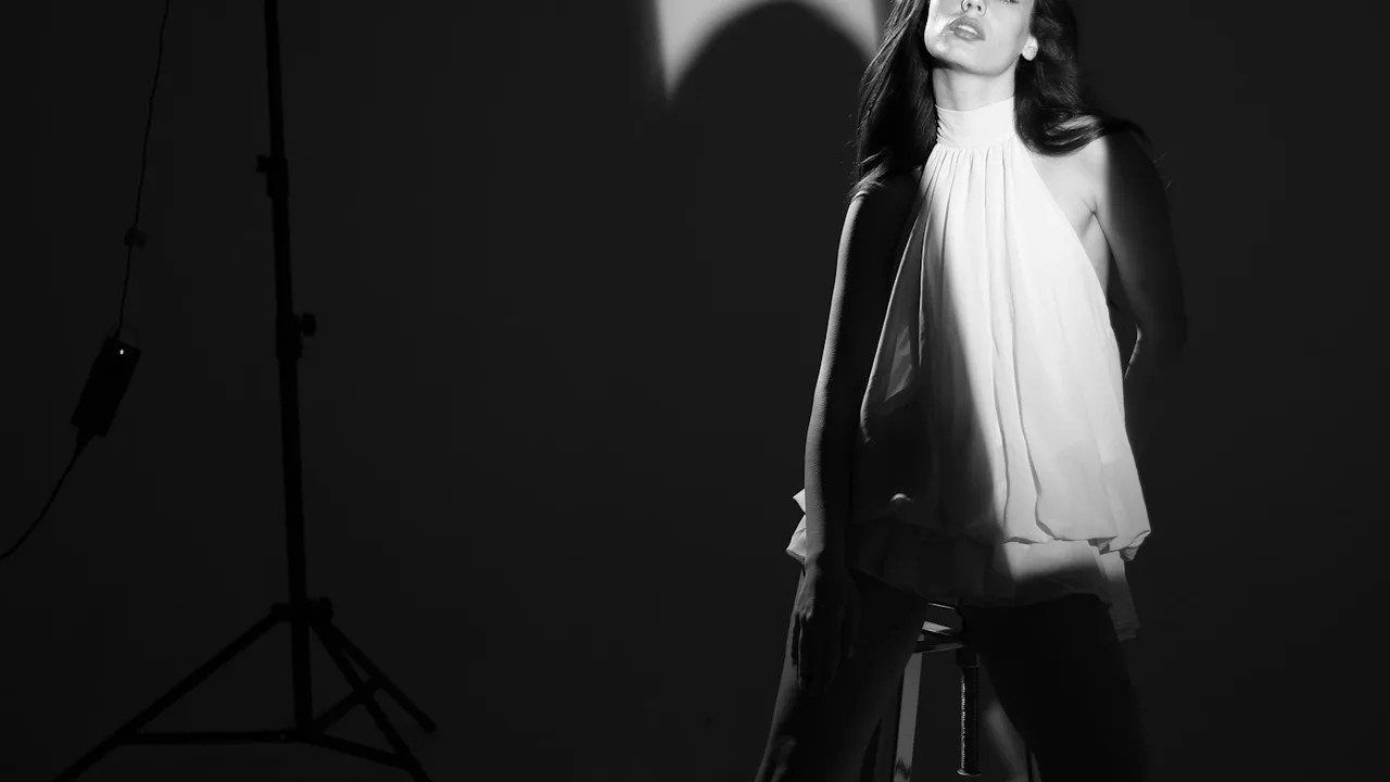 Vogue editorial high-fashion studio portrait with directional strobe lighting and sculptural pleated fabric